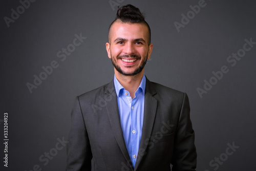 Portrait of happy bearded Turkish businessman in suit smiling