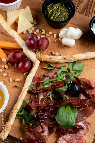 Close up macro of wine platter with assorted snacks such as grissini, cheese, sliced meat and nuts on wooden board