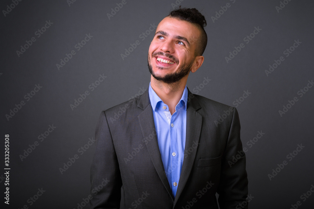 Portrait of happy bearded Turkish businessman in suit thinking Portrait of happy bearded Turkish businessman in suit thinking