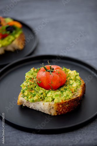 Toast avocado, tomato and shnit on a black dish photo