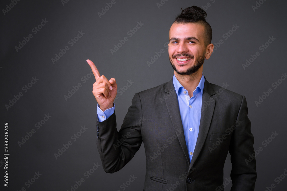 Portrait of happy bearded Turkish businessman in suit pointing up Portrait of happy bearded Turkish businessman in suit pointing up