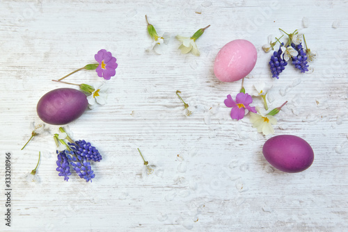 Photography easter eggs painted in pink and purple on a table among spring flowers and petal