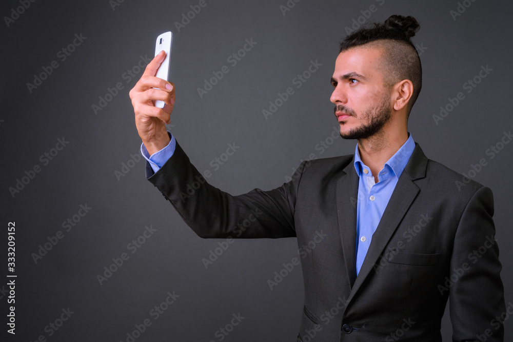 Profile view of handsome bearded Turkish businessman in suit taking selfie Profile view of handsome bearded Turkish businessman in suit taking selfie