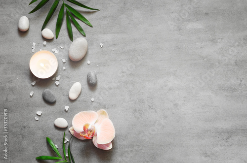 Spa concept on stone background, palm leaves, flower, candle and zen, grey stones, top view, copy space.