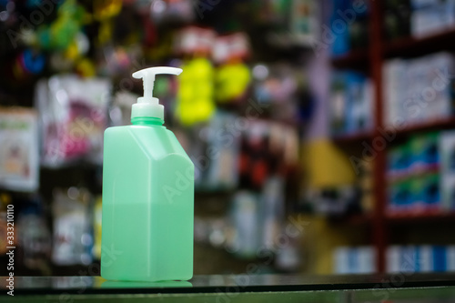 Pump type hand sanitizer/disinfectant on a counter table in a business establishment to prevent the spread of COVID-19 with goods in the background