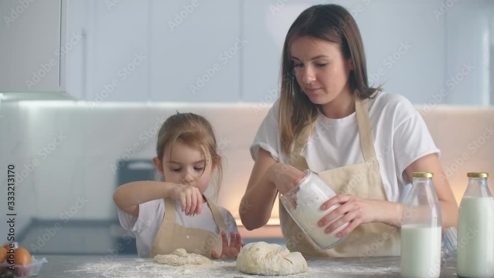 Put flour on the dough together while kneading it with your hands. Making a pizza blank with my daughter. Loving mother and daughter cook together according to a family recipe Put flour on the dough together while kneading it with your hands. Making a pizza blank with my daughter. Loving mother and daughter cook together according to a family recipe