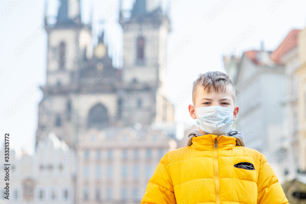 Portrait of a boy wearing medical mask on the old town square in Prague. Coronavirus epidemic concept