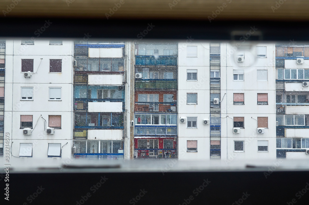 Apartments exterior seen from a window of a building across it in a snowy day