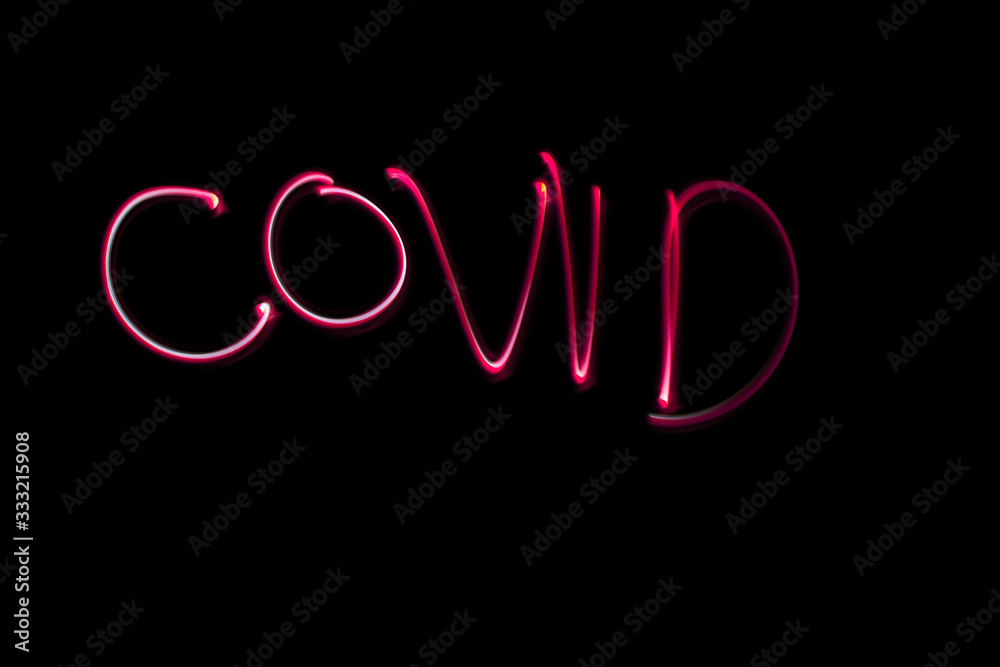 Covid name hand drawn with a flashlight and red light on black background