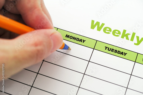 Person writing weekly schedule with ballpoint pen photo