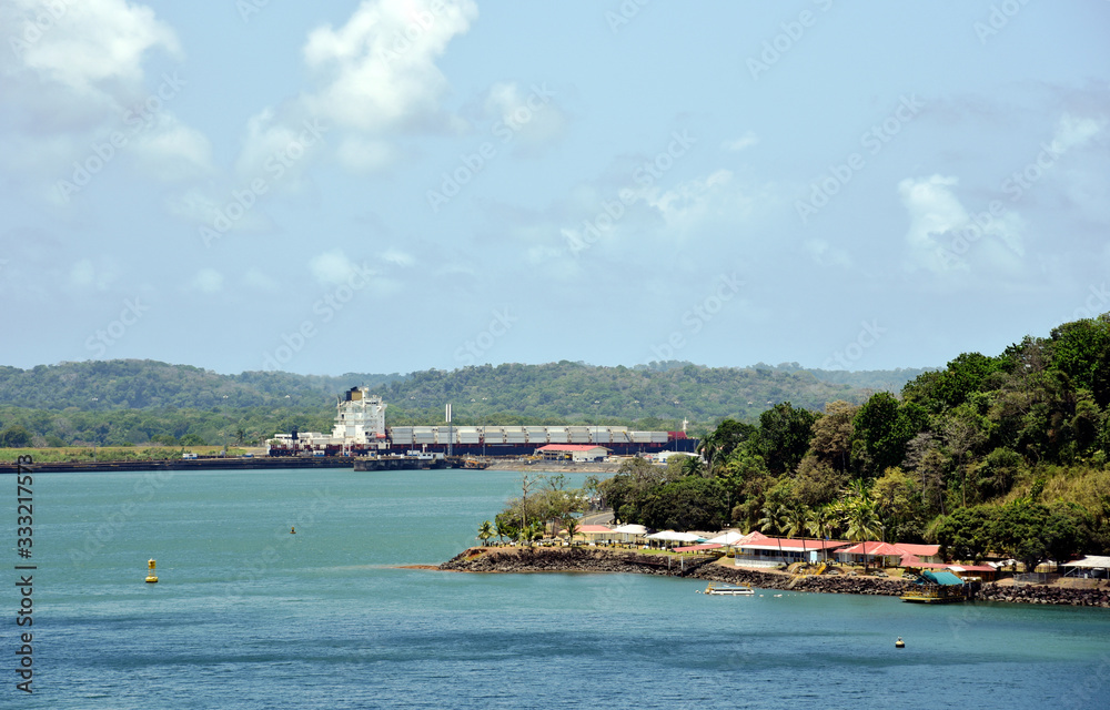 Green landscape of Panama Canal, cargo ship on the background entering Gatun Locks. 