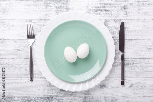 Spring table setting. Green mint plate, Easter eggs and cutlery on wooden background. Easter composition. Copy space. Top view