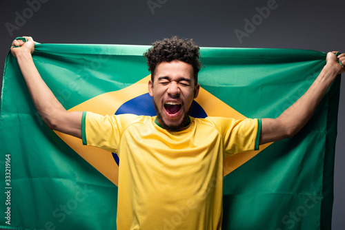 Bilde på lerret emotional african american football fan shouting and holding brazilian flag on g