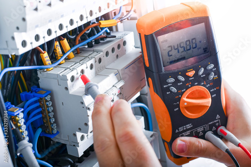 Electrician installing electric cable wires of fuse switch box.