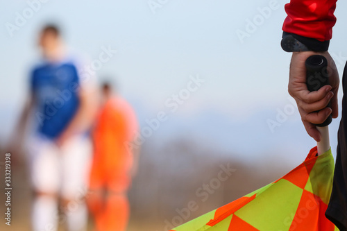 Sport concept. Soccer, football assistant referee is standing and holding the flag. Blurred sky and players background. photo