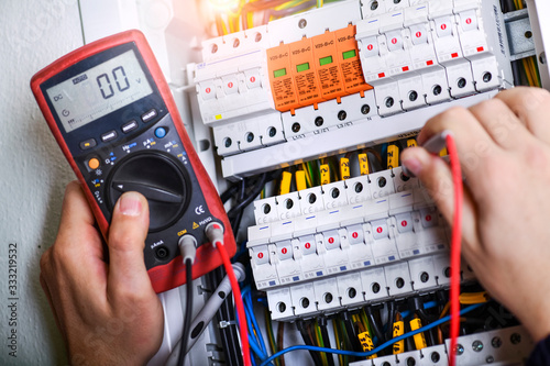 Electrician installing electric cable wires and fuse switch box.