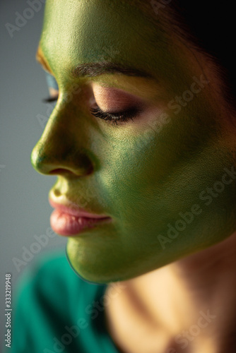 female soccer fan with painted brazilian flag on face isolated on grey