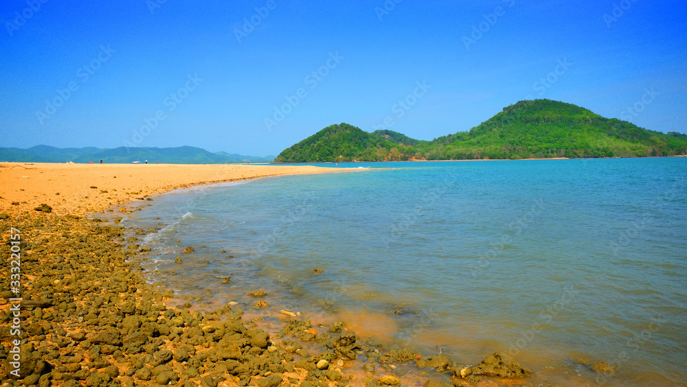 Tropical island bay, stone reef and mountain view background on summer season.