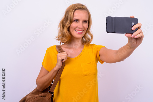 Portrait of happy beautiful blonde tourist woman with backpack taking selfie