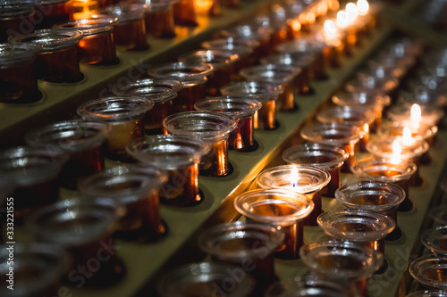 Burning and extinct funeral candles in a church, stand in a row