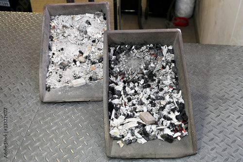 Zwei Metallschalen mit menschlicher Asche und Knochenfragmenten nach der Einäscherung in einem Krematorium