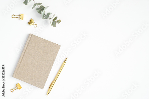 Flat lay home office desk. Female workspace with paper notepad and golden accessories on white background. Top view feminine workplace