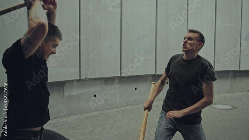 men with baseball bats fighting on street