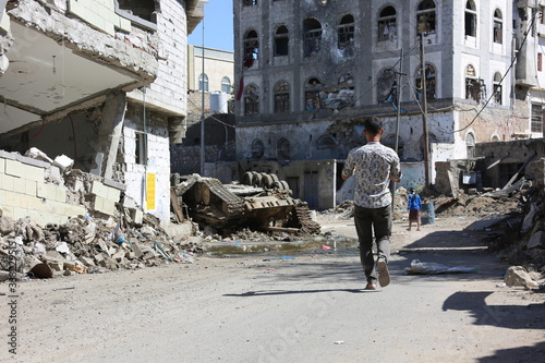 A man walks past the houses destroyed by war and violent fighting between the National Army and the Houthi militia in the city of Taiz, Yemen photo