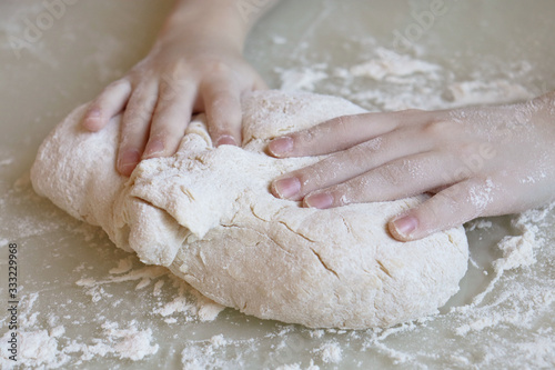 Making dough from flour. The child kneads the dough closeup