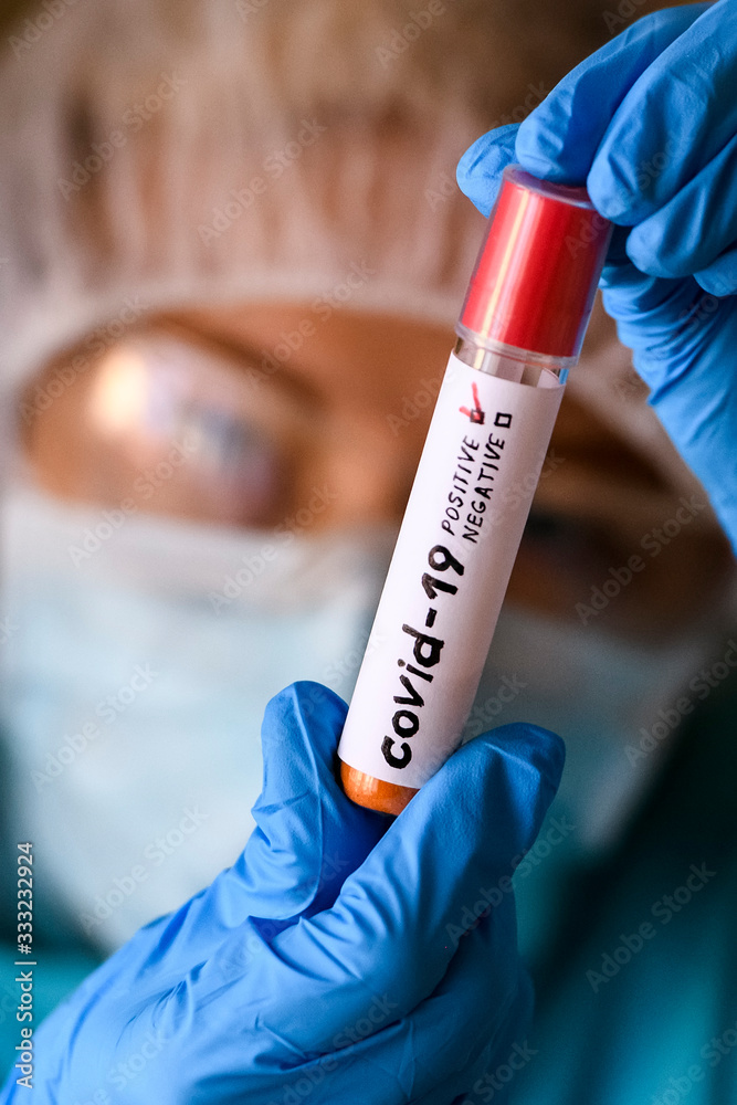 Fototapeta premium Woman in protective suit hold test tube with positive result infected with coronavirus COVID - 19.