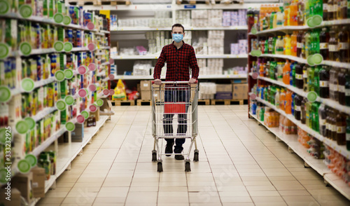 Man in protective mask shopping in supermarket pushing trolley during epidemic photo