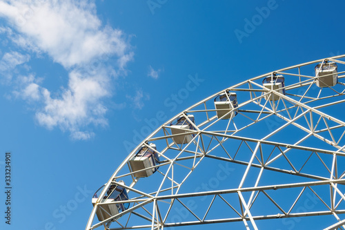Bottom view of part white ferris wheel on background of blue sky and cloud in sunny day.