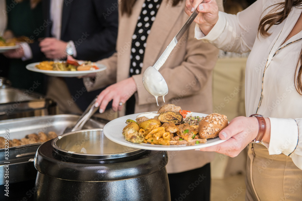 People are serving themselves food from a catering buffet party 