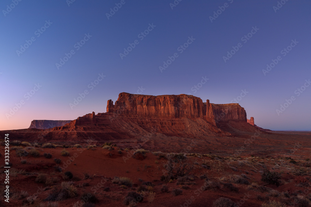The last rays of the setting sun illuminate iconic view of Monument Valley on the border between Arizona and Utah, USA