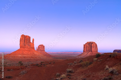 The last rays of the setting sun illuminate famous Buttes of Monument Valley on the border between Arizona and Utah, USA © Artem