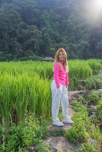Asian woman in pink sweater smiling in green rice field