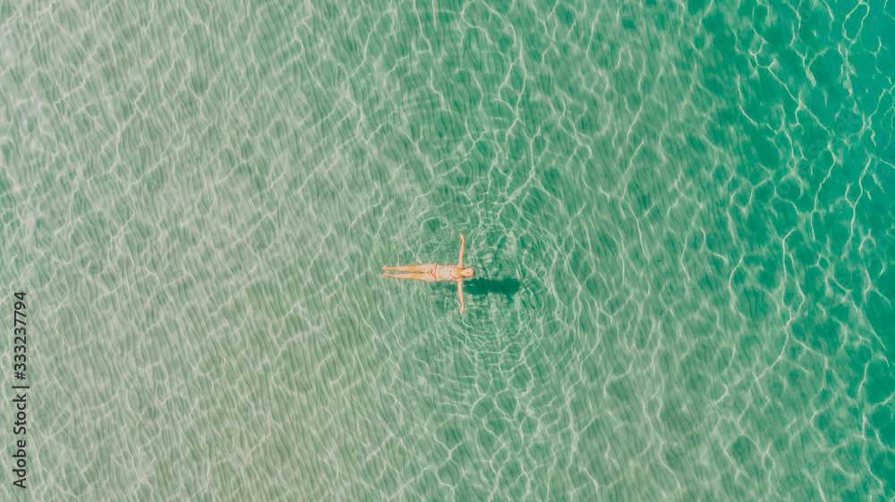 Fototapeta premium Girl enjoying a sunny and calm day in the sea. Top view. Best relaxation. Summer afternoon by the sea