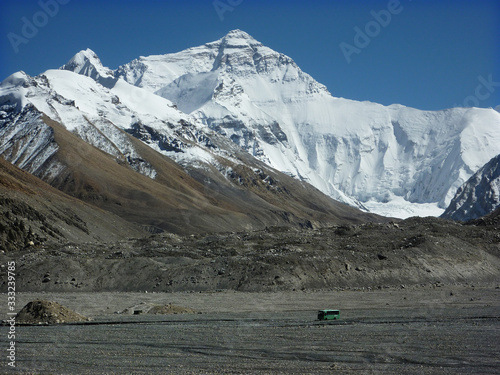 Green autobus crossing a plain barren landscape on its way to Mount Everest base camp on Tibetan side