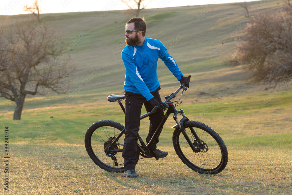 Cyclist in pants and fleece jacket on a modern carbon hardtail bike with an air suspension fork. The guy on the top of the hill rides a bike.