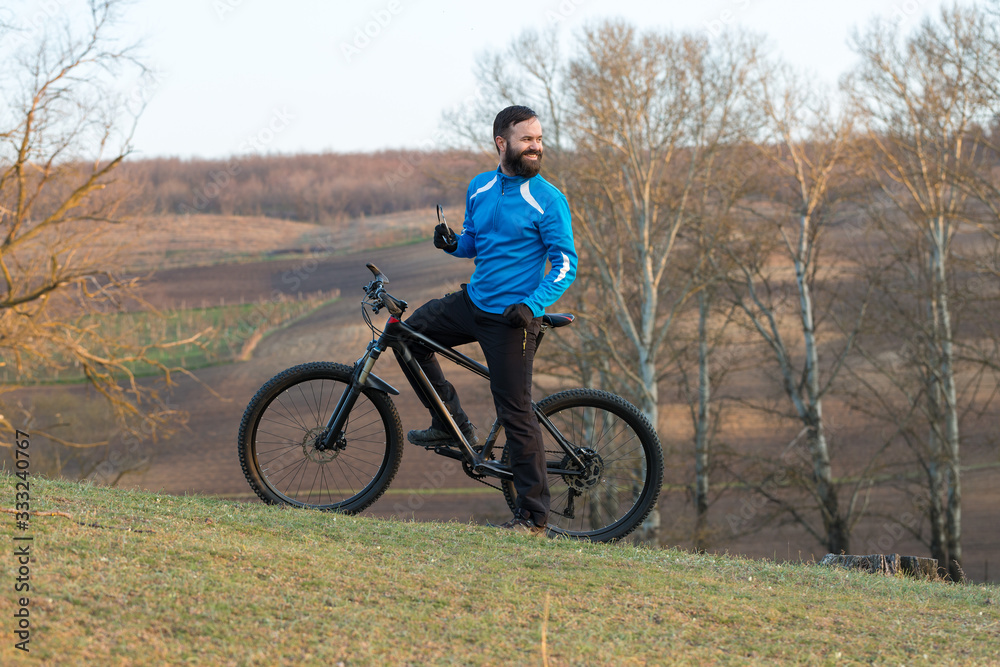 Cyclist in pants and fleece jacket on a modern carbon hardtail bike with an air suspension fork. The guy on the top of the hill rides a bike. Cyclist in pants and fleece jacket on a modern carbon hardtail bike with an air suspension fork. The guy on the top of the hill rides a bike.