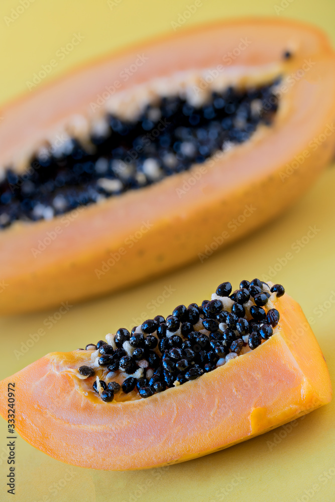 Papaya pieces with seeds on yellow background Papaya pieces with seeds on yellow background