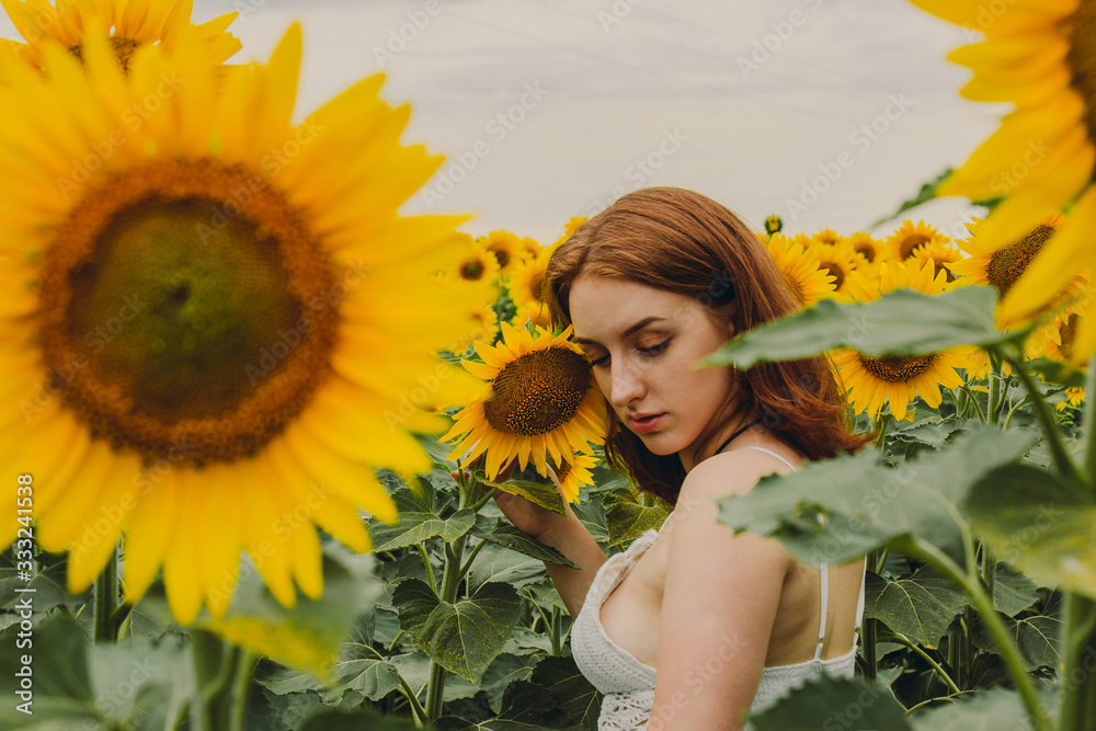 Portrait of a beautiful, cute, sexy red-haired girl in a white dress with sunflower flowers. Emotion of pleasure, freedom concept, lifestyle. Portrait of a beautiful, cute, sexy red-haired girl in a white dress with sunflower flowers. Emotion of pleasure, freedom concept, lifestyle.