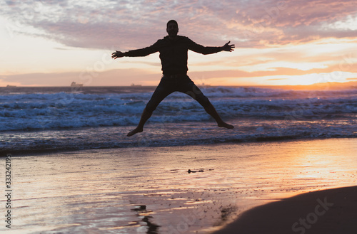 Chico joven haciendo disfrutando de la playa al atardecer