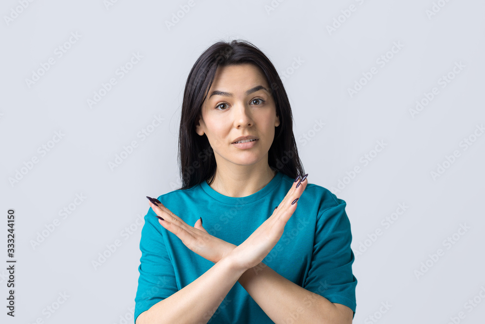Girl disapproving with no crossing hands sign make negation gesture. Portrait of pretty woman on grey background Girl disapproving with no crossing hands sign make negation gesture. Portrait of pretty woman on grey background
