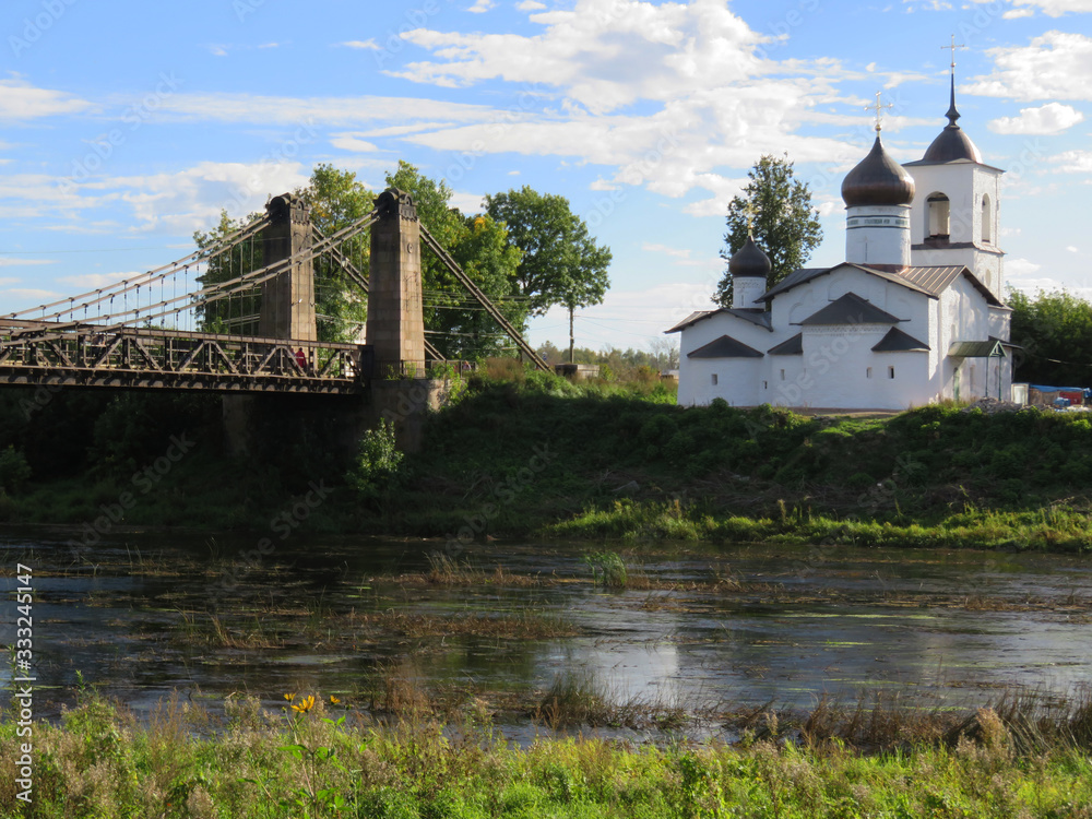 Russia. Pskov region. City Ostrov.  The Great River. This suspension bridge is 100 years old. There is a temple on the Bank of the Great river. 