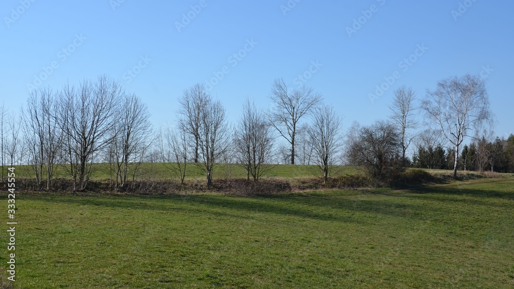 Naturlandschaft im Frühling mit Wiesen und Bäumen Naturlandschaft im Frühling mit Wiesen und Bäumen