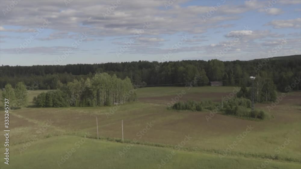 Drone flying over a field towards a forest and lake Drone flying over a field towards a forest and lake