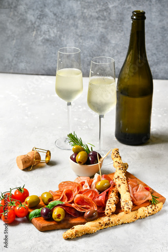 Traditional Italian appetizers ( antipasto ) : salami, bresaola, prosciutto, olives. Aperitif in Italy in Florence, Rome, aperitif in Milan. Two glasses of Prosecco and sticks of cereal bread