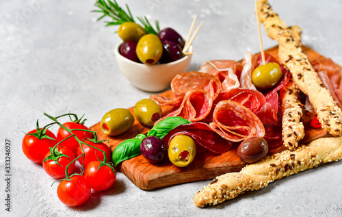 Traditional Italian appetizers antipasto : salami, bresaola, prosciutto parma, olives. Aperitif in Italy in Florence, Rome, aperitif in Milan. Two glasses of Prosecco and sticks of cereal bread