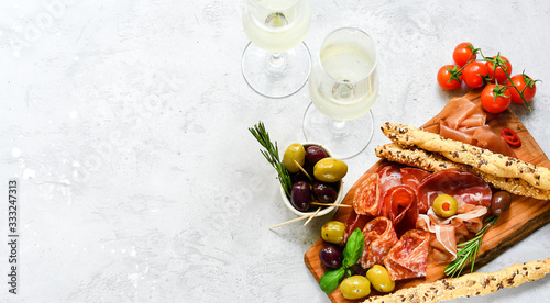 Traditional Italian appetizers ( antipasto ) : salami, bresaola, prosciutto, olives. Aperitif in Italy in Florence, Rome, aperitif in Milan. Two glasses of Prosecco and sticks of cereal bread